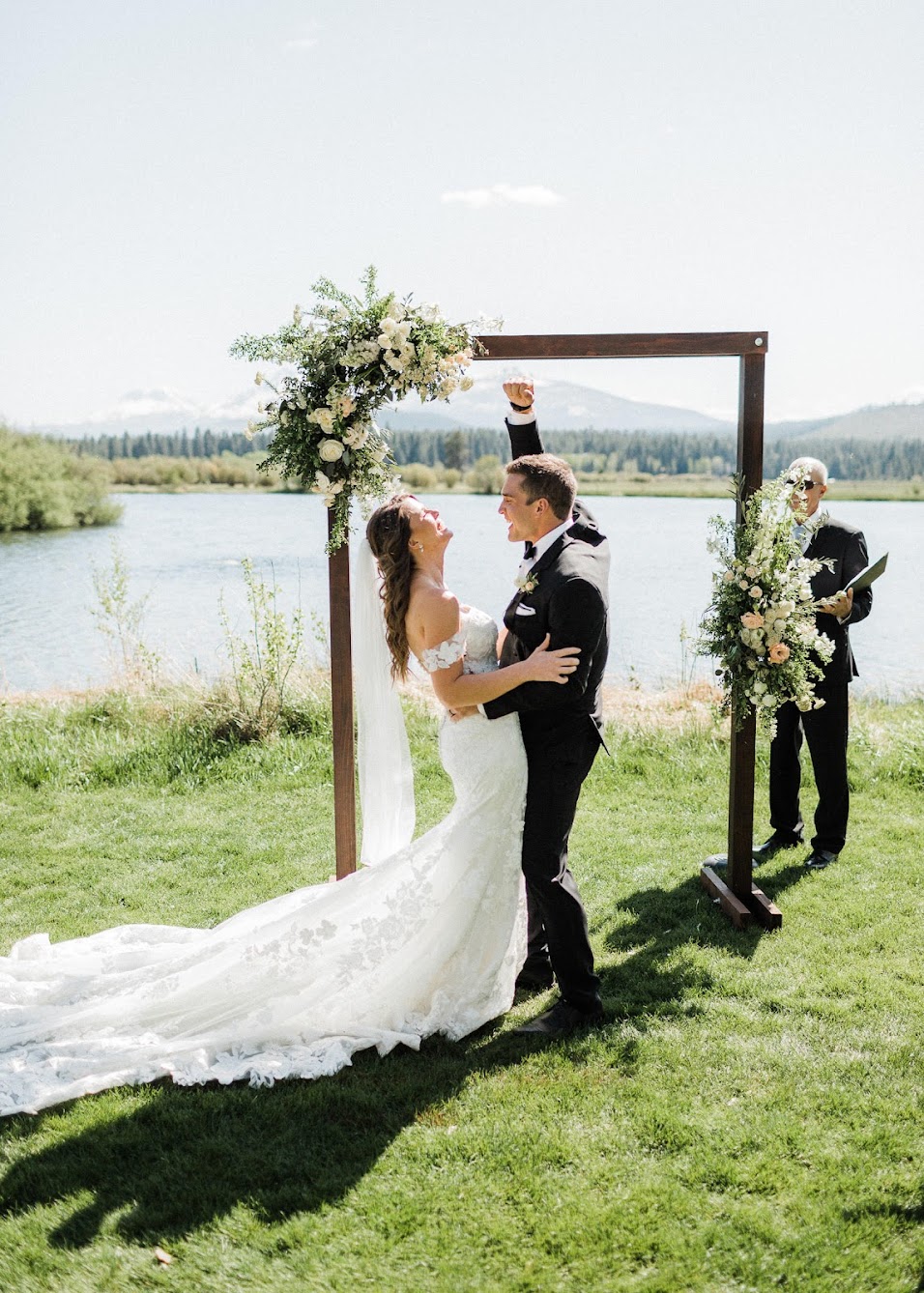 groom holding his hand up in the air saying "YEAH!" while he holds his bride.