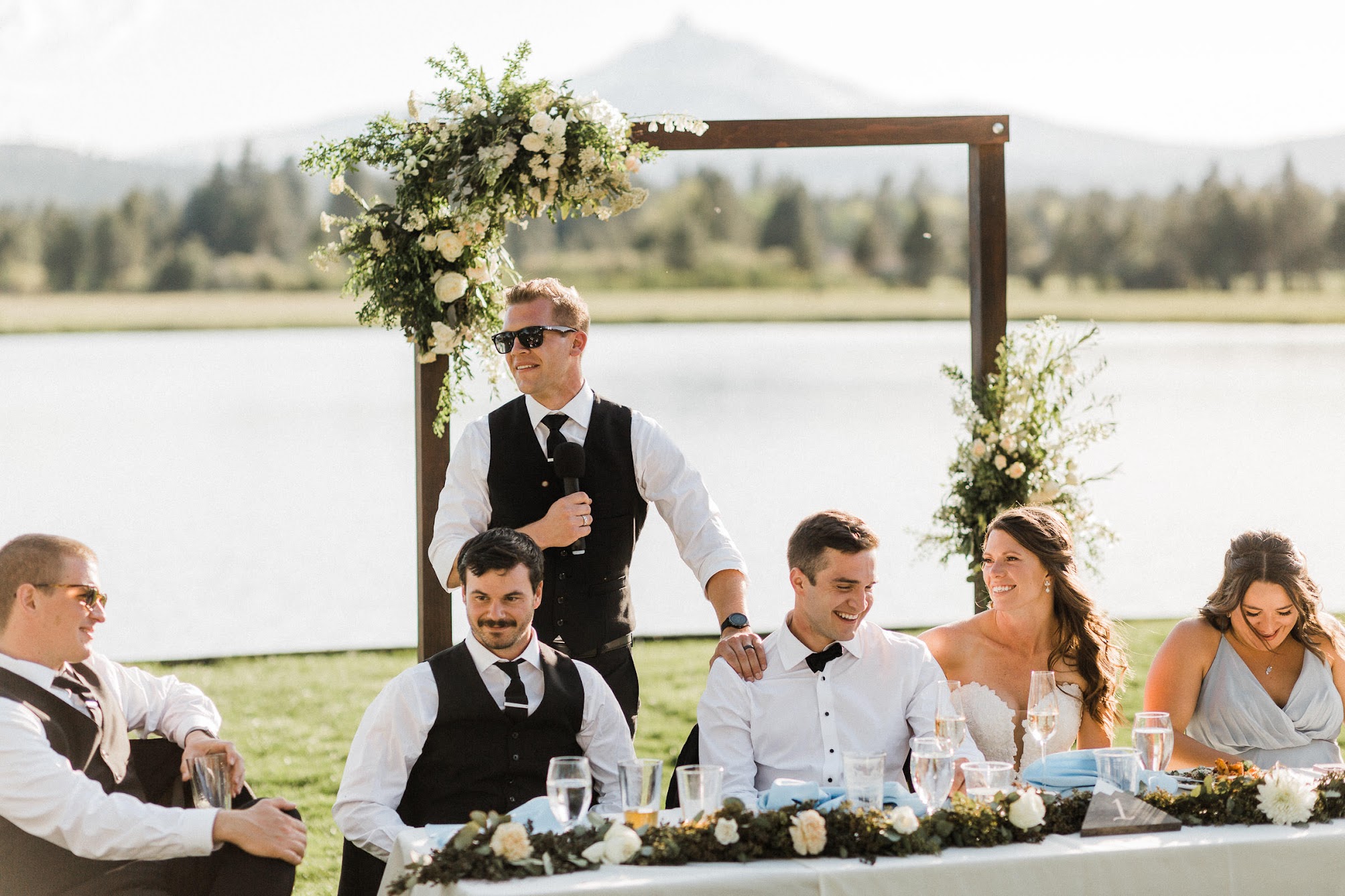the best man standing with his hand on the grooms shoulder giving a speech 