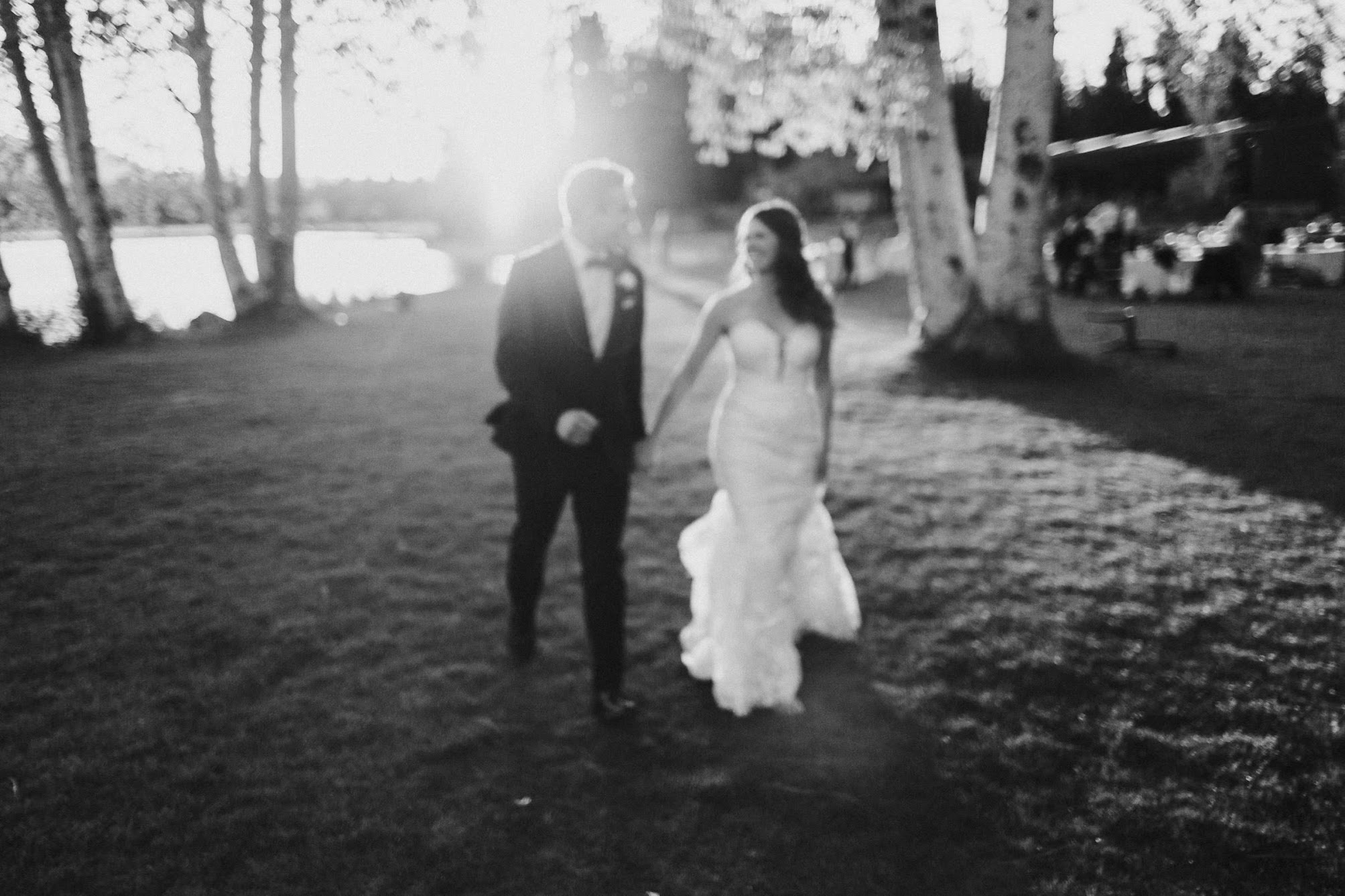 blurry photo of the bride and groom holding hands with the sun behind them 