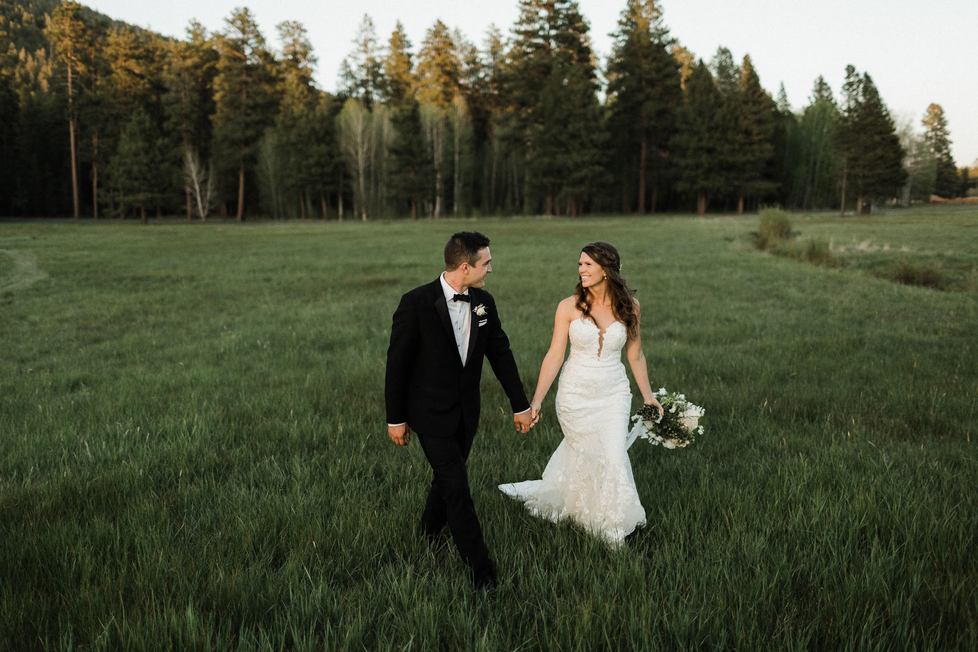 bride and groom walking towards us holding hands, looking at each other 
