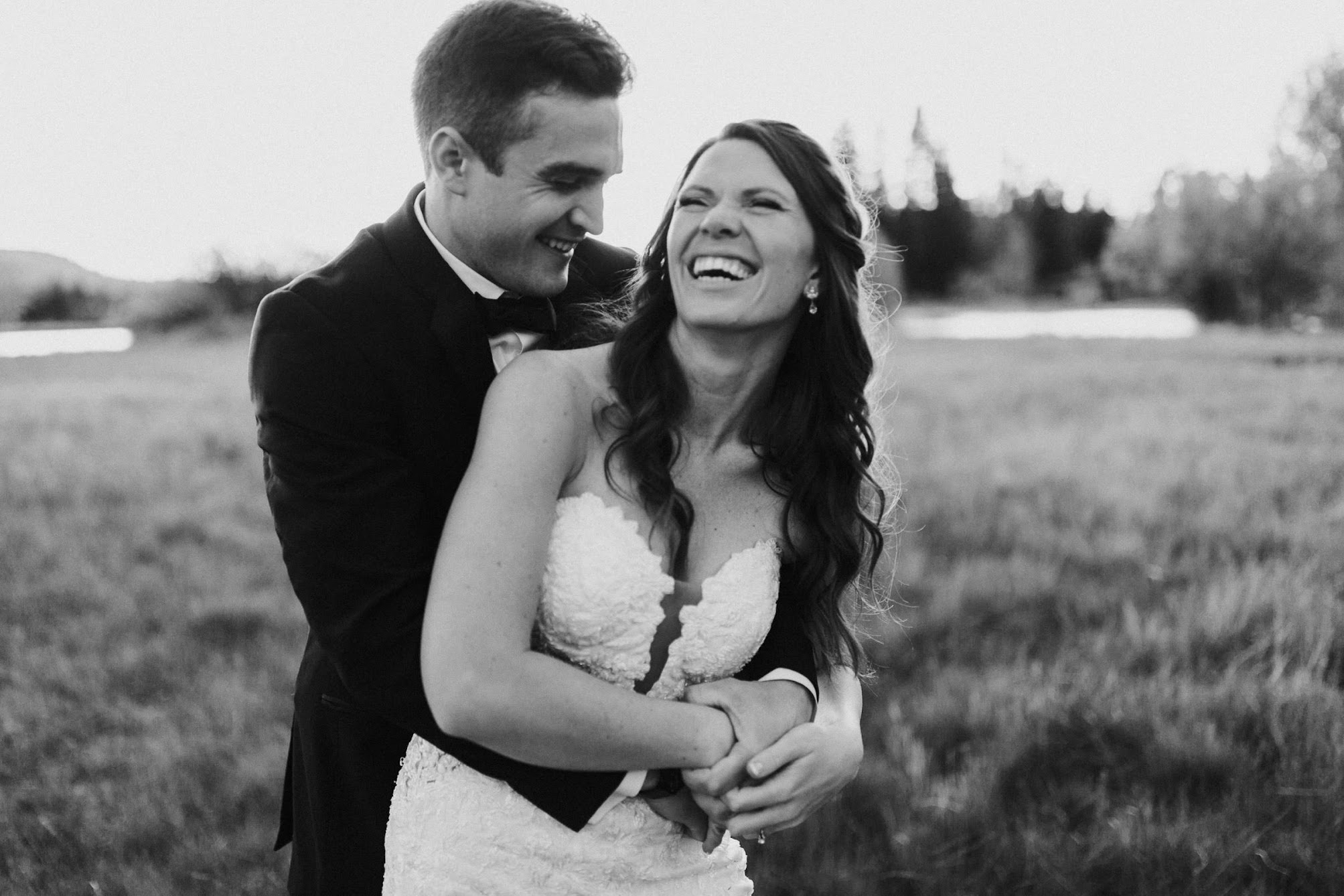 groom holding the bride from behind they are both laughing 
