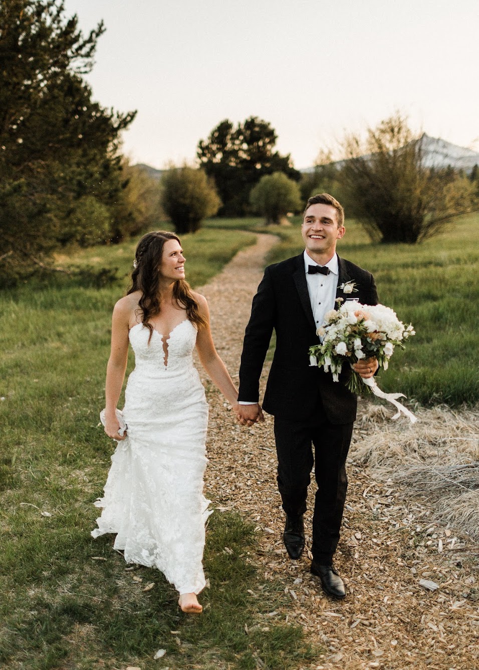 bride and groom walking down, groom is holding the brides bouquet 