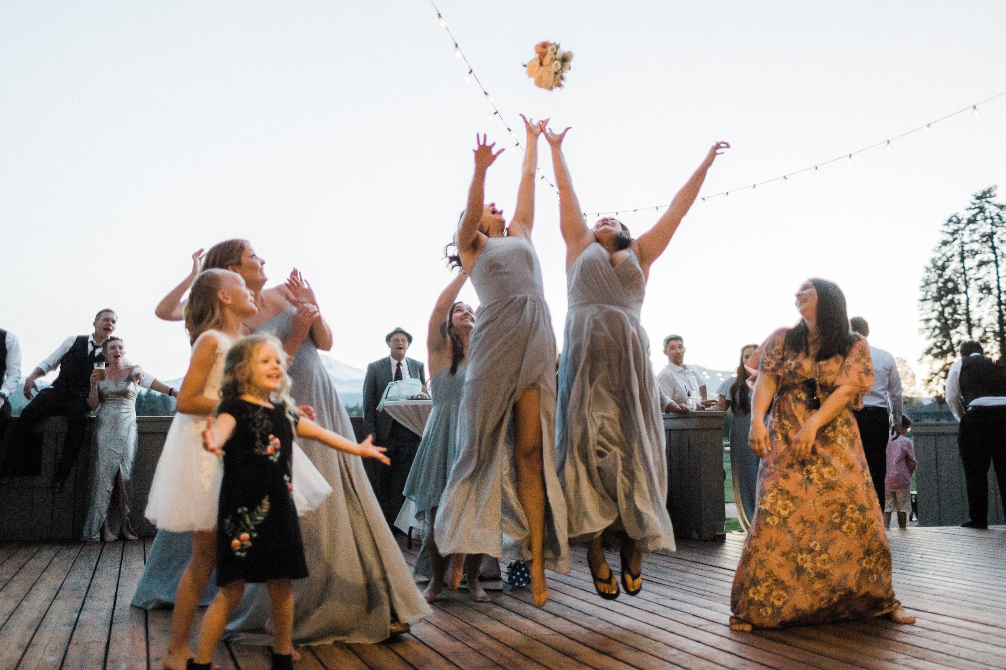 two bridesmaid jumping up to catch the bridal bouquet 