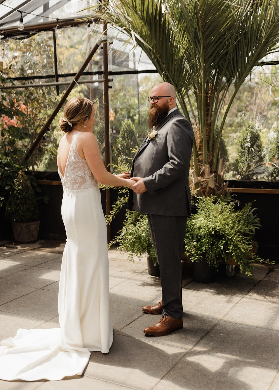 A bride and groom standing together with their hands held tight.