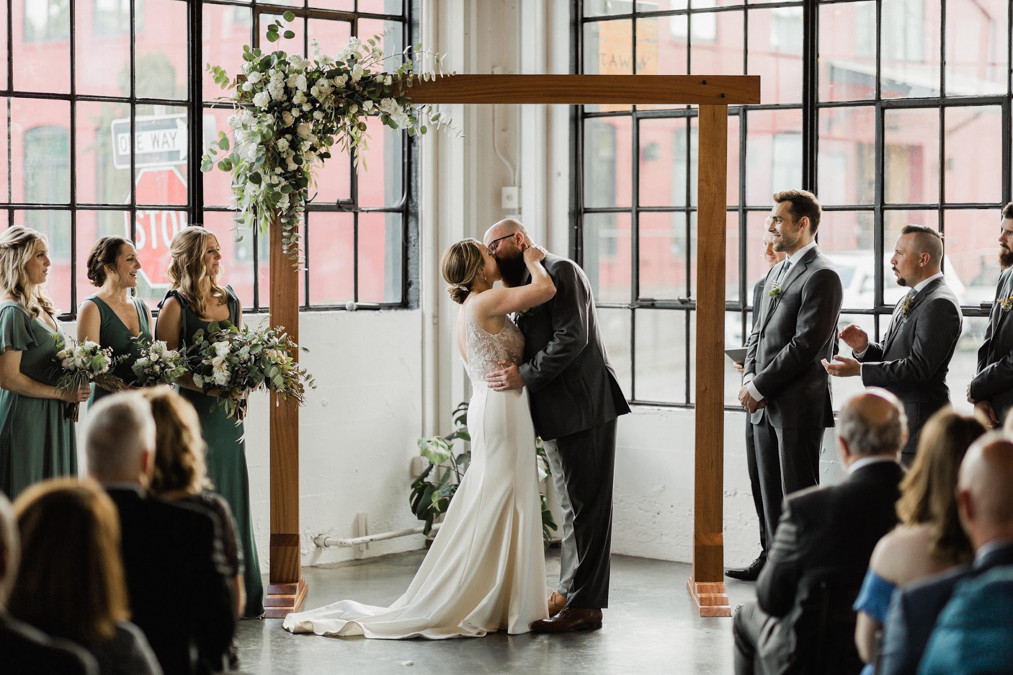 the bride and groom kissing under their arbor 