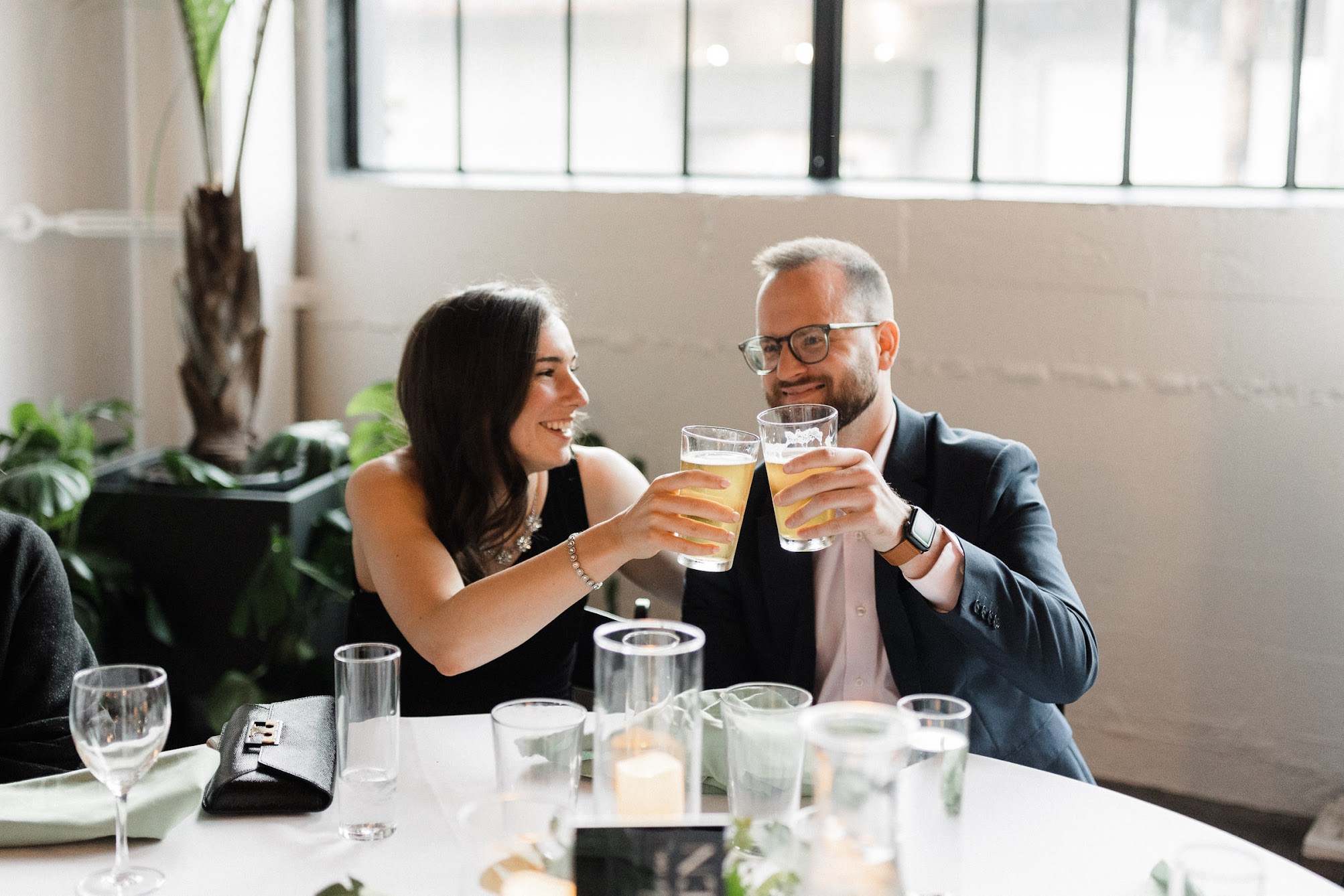 a young couple holding beer and saying "cheers"