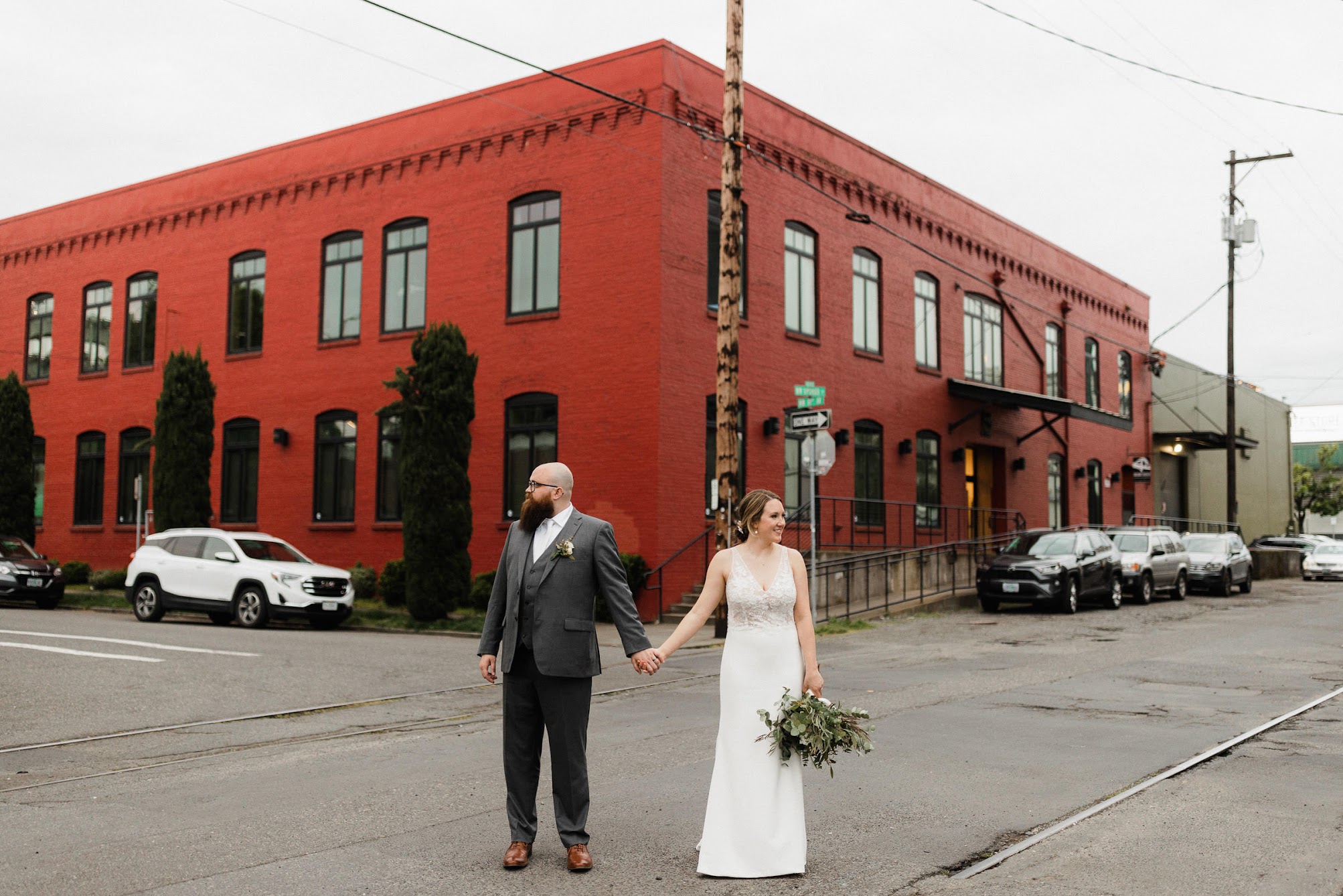 bride and groom holding hands in the middle of a street 