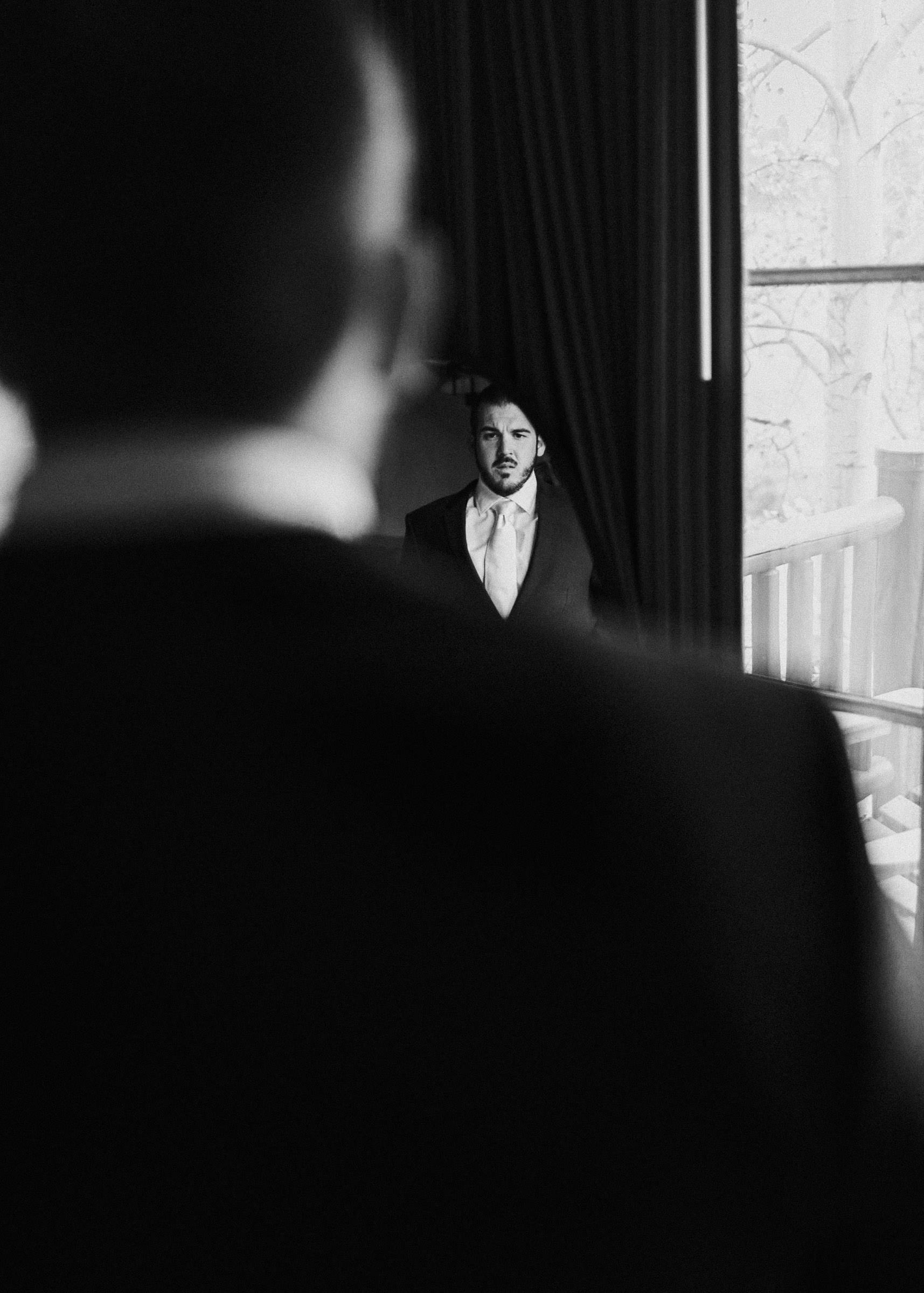 Groom's reflection in a standing mirror as a he finishes getting dressed