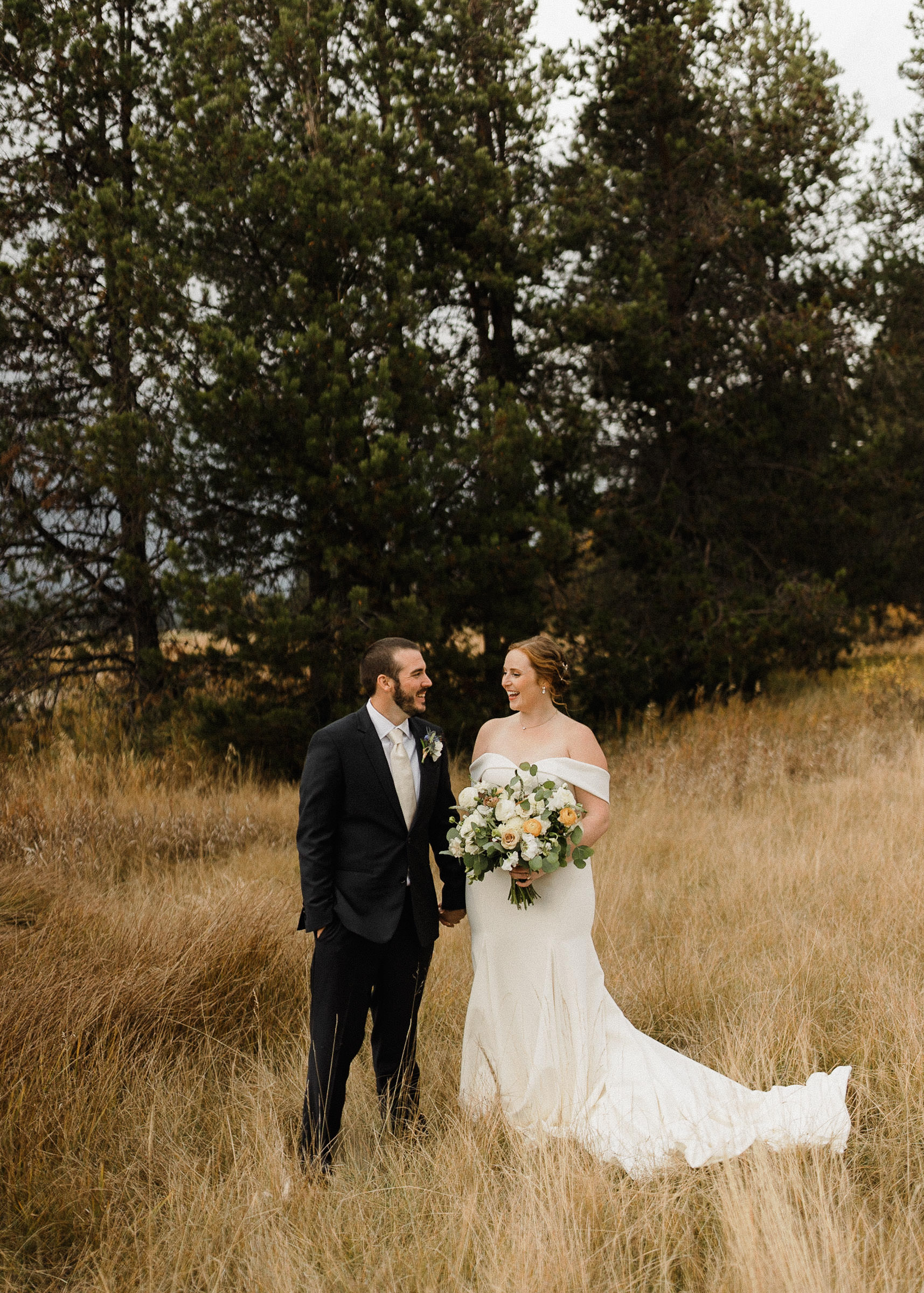 Bride and groom pose for portraits in a field at Sunriver Resort