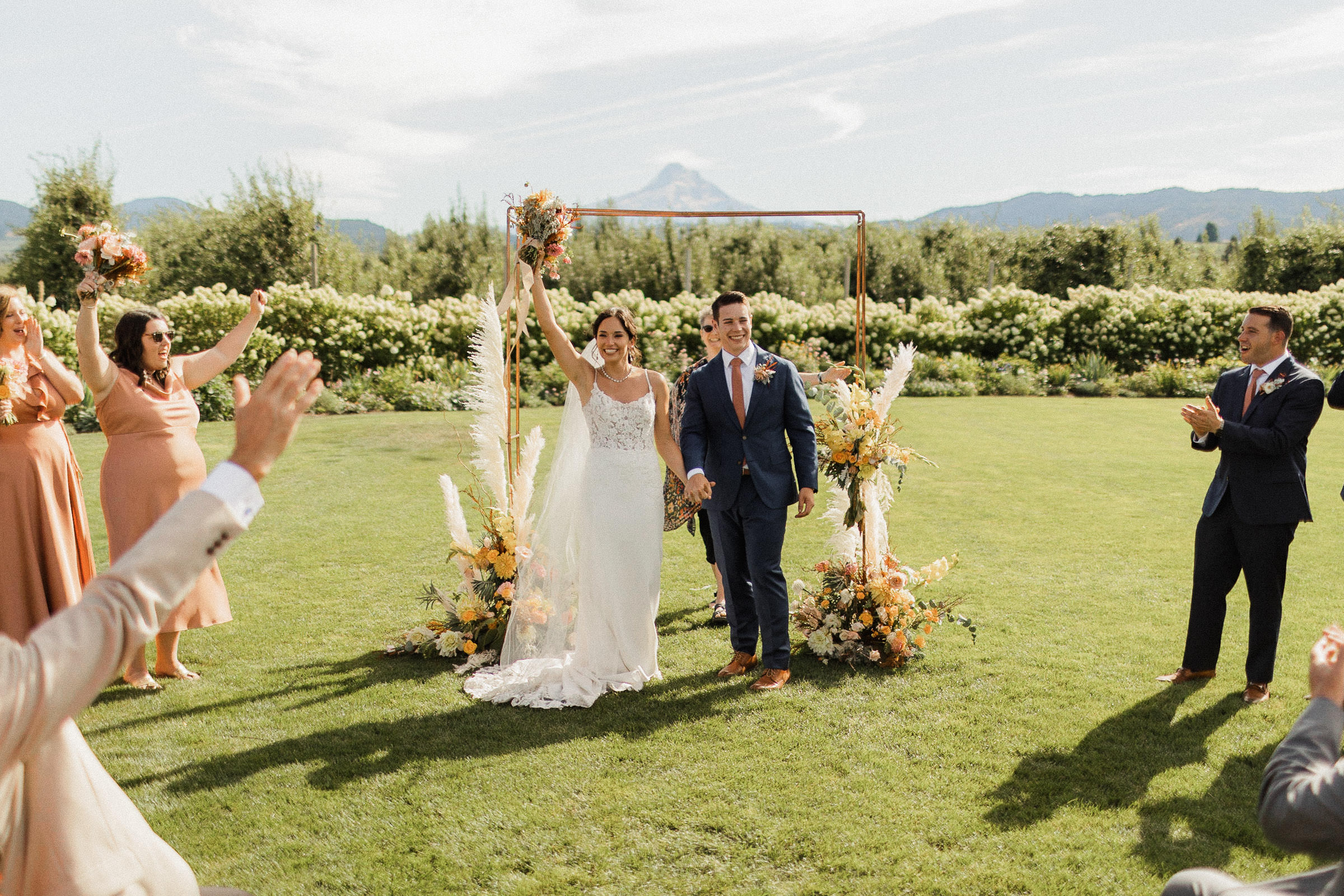 Bride and groom beam as guests cheer at conclusion of wedding ceremony