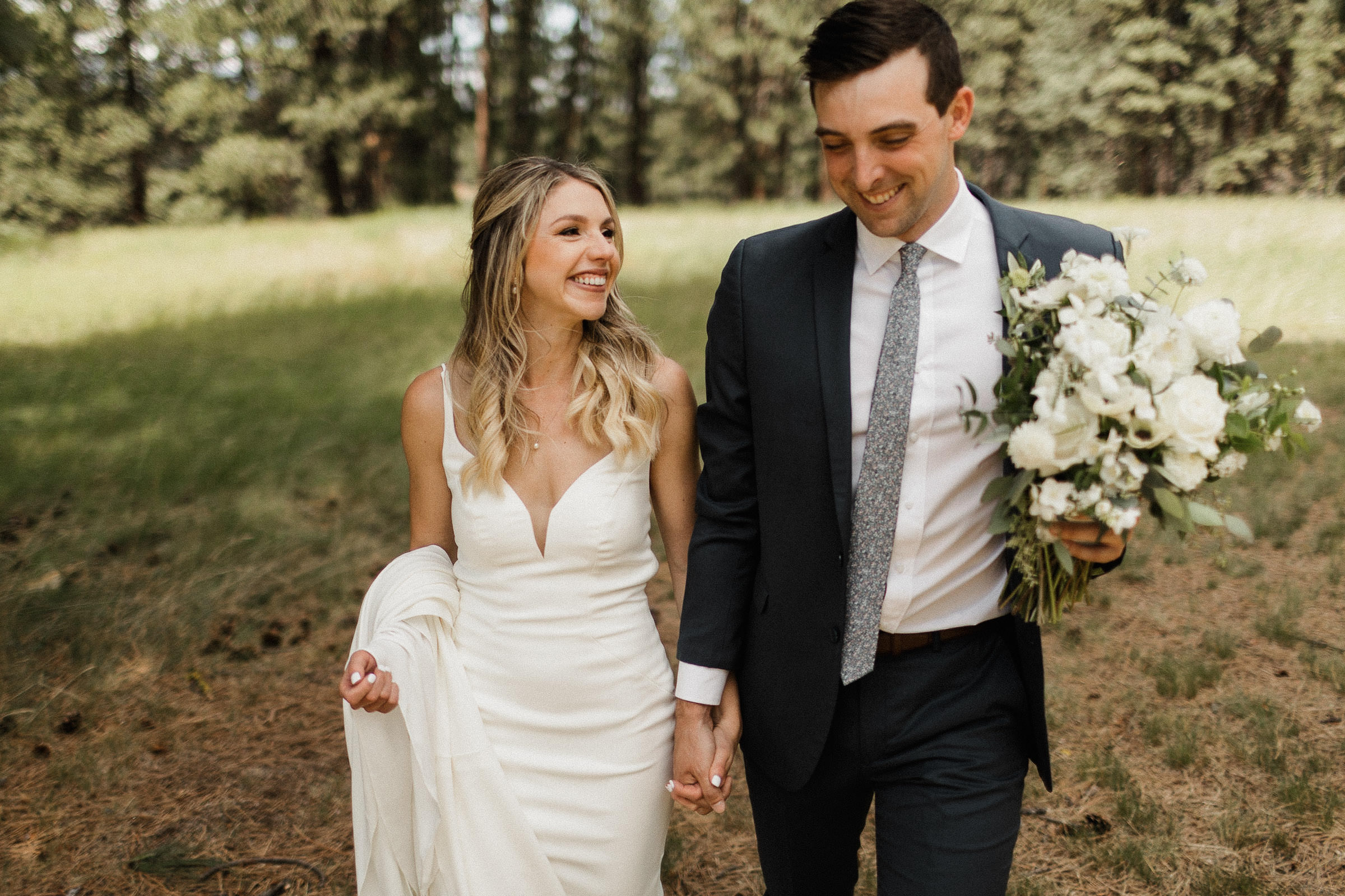 Bride and groom smiling, holding hands and walking 