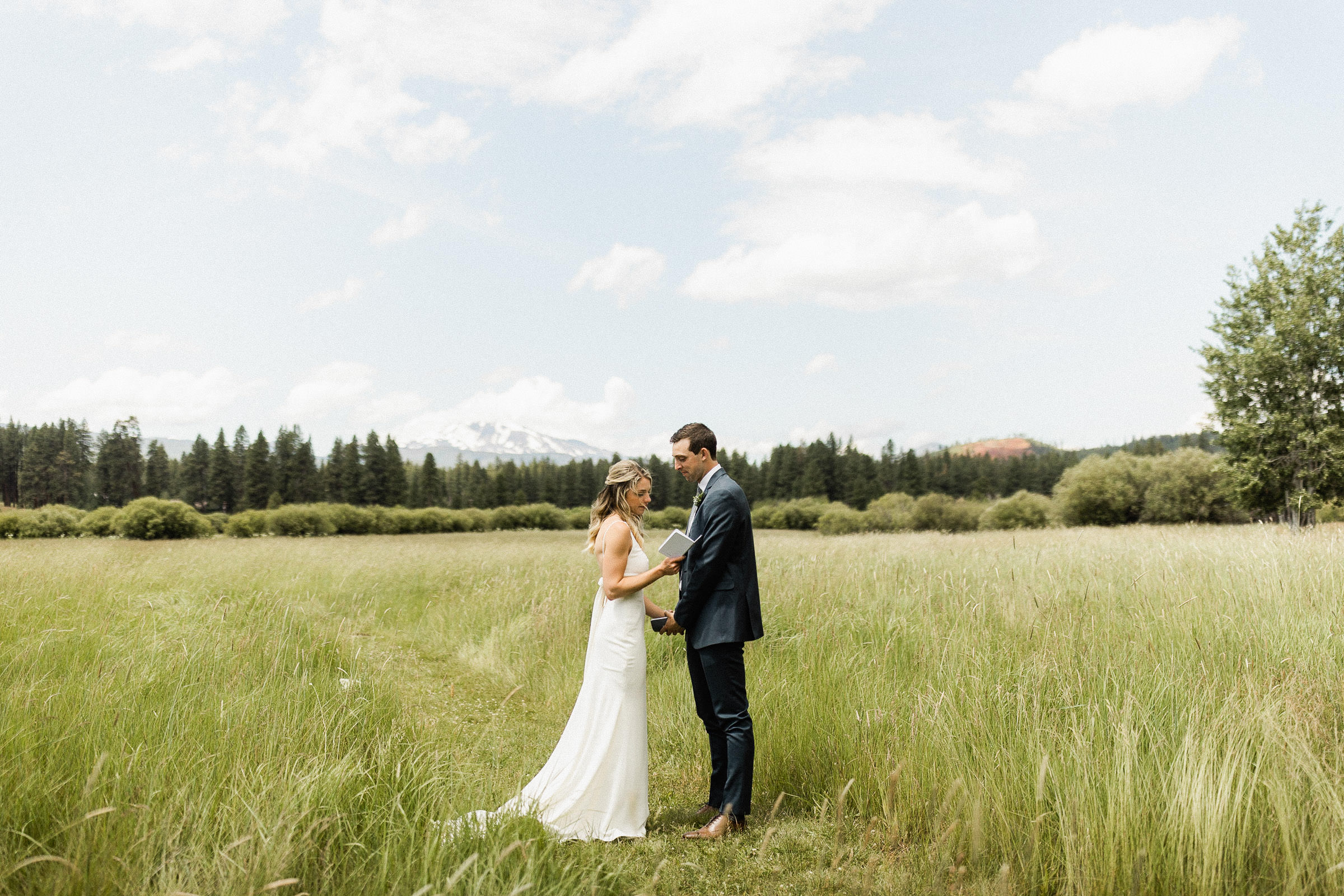 The bride reads her vows to groom during a private vow reading in a field
