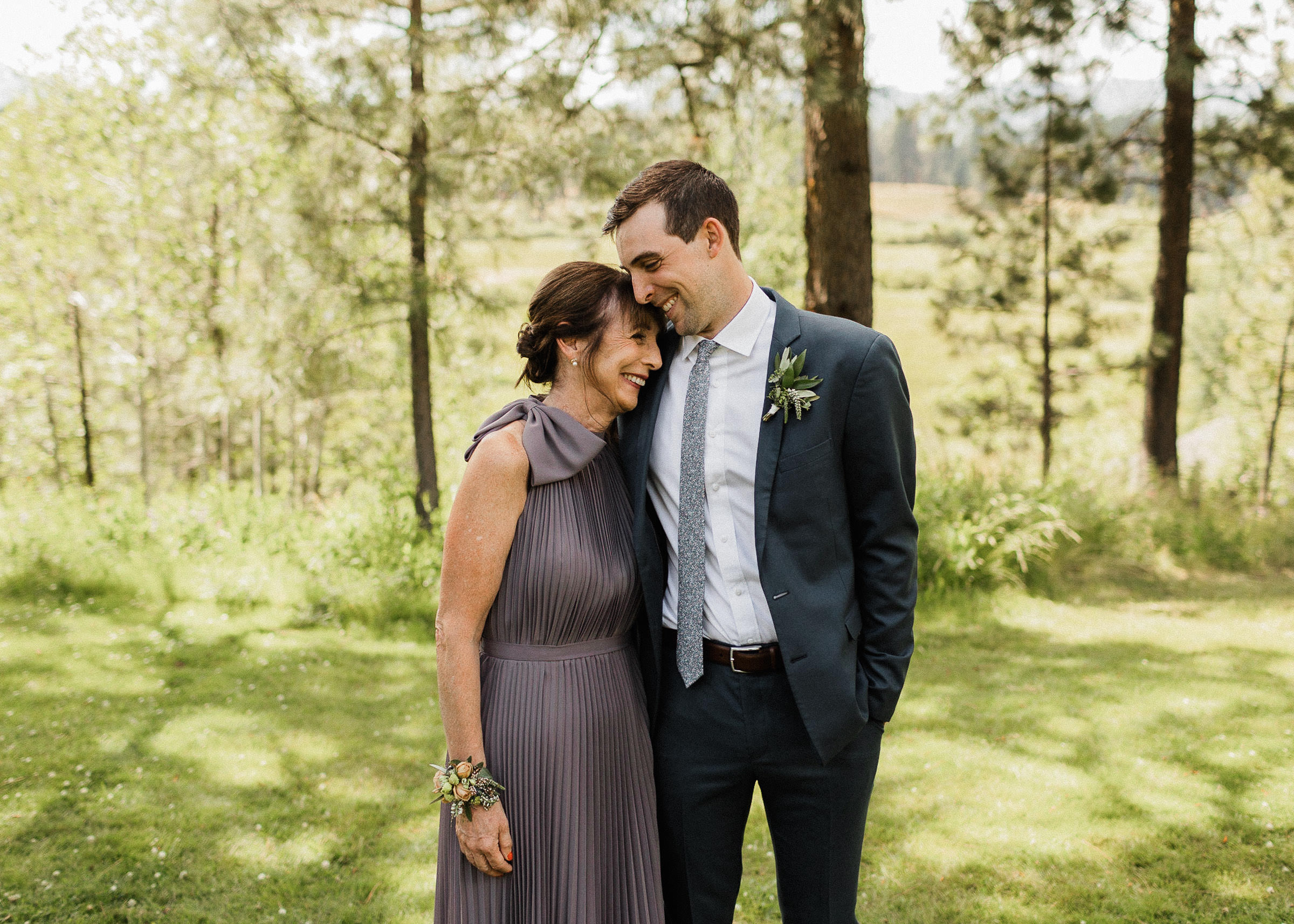 Groom and his mom laugh and lean heads together