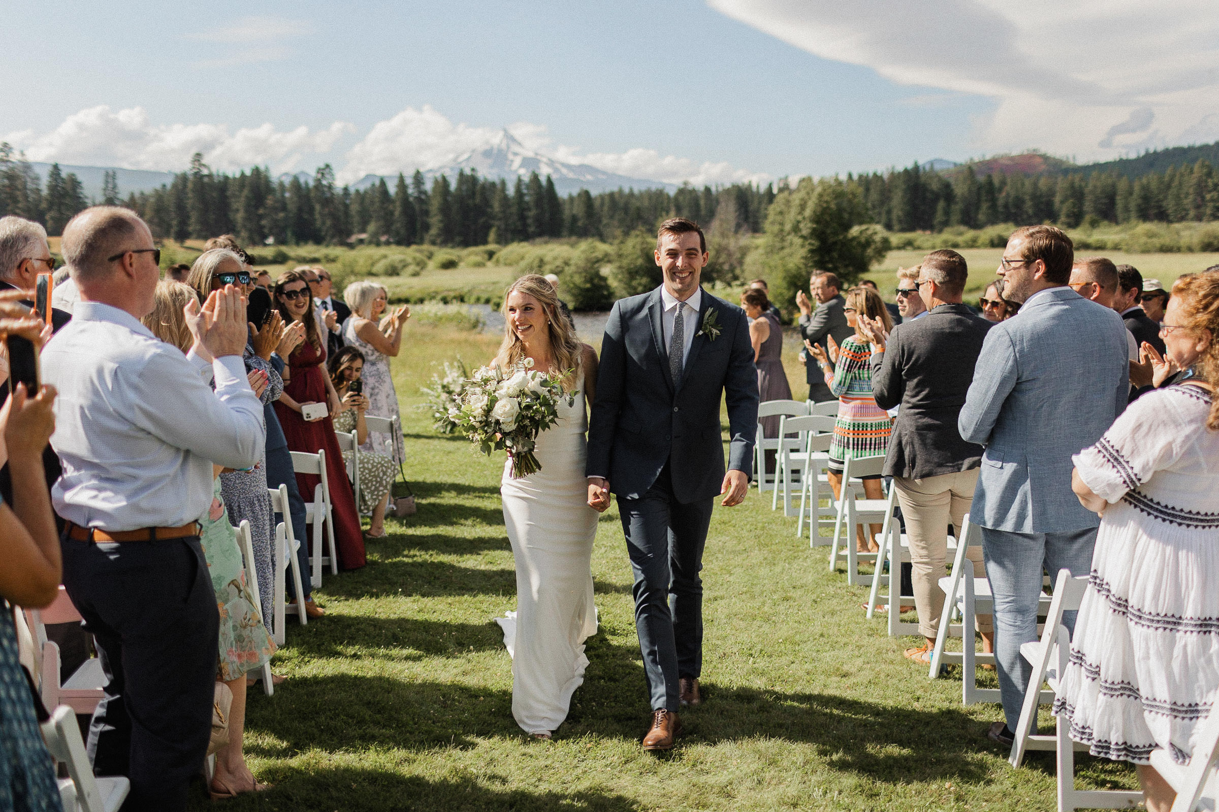 Bride and groom smile as they recess down the aisle after the ceremony