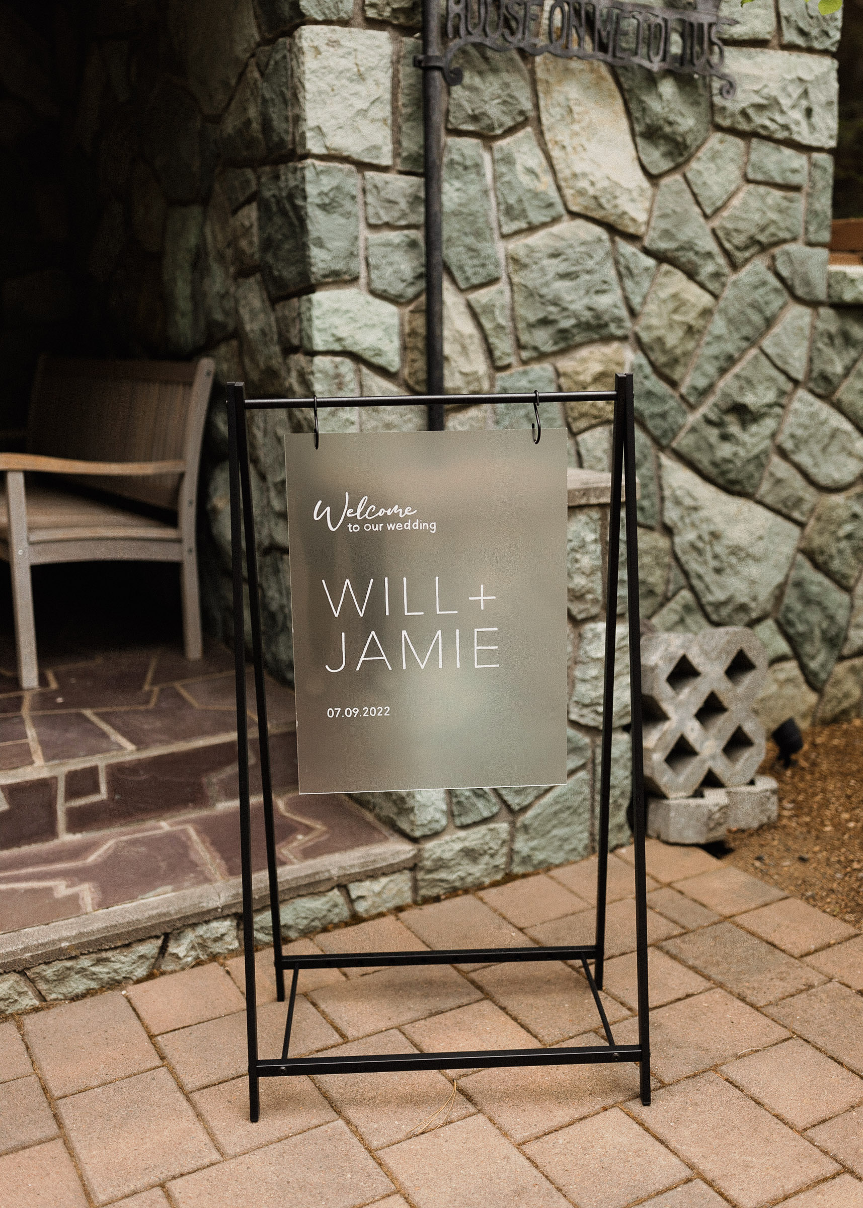 A translucent sign reading "Welcome to the wedding of Will + Jamie 07.09.2022