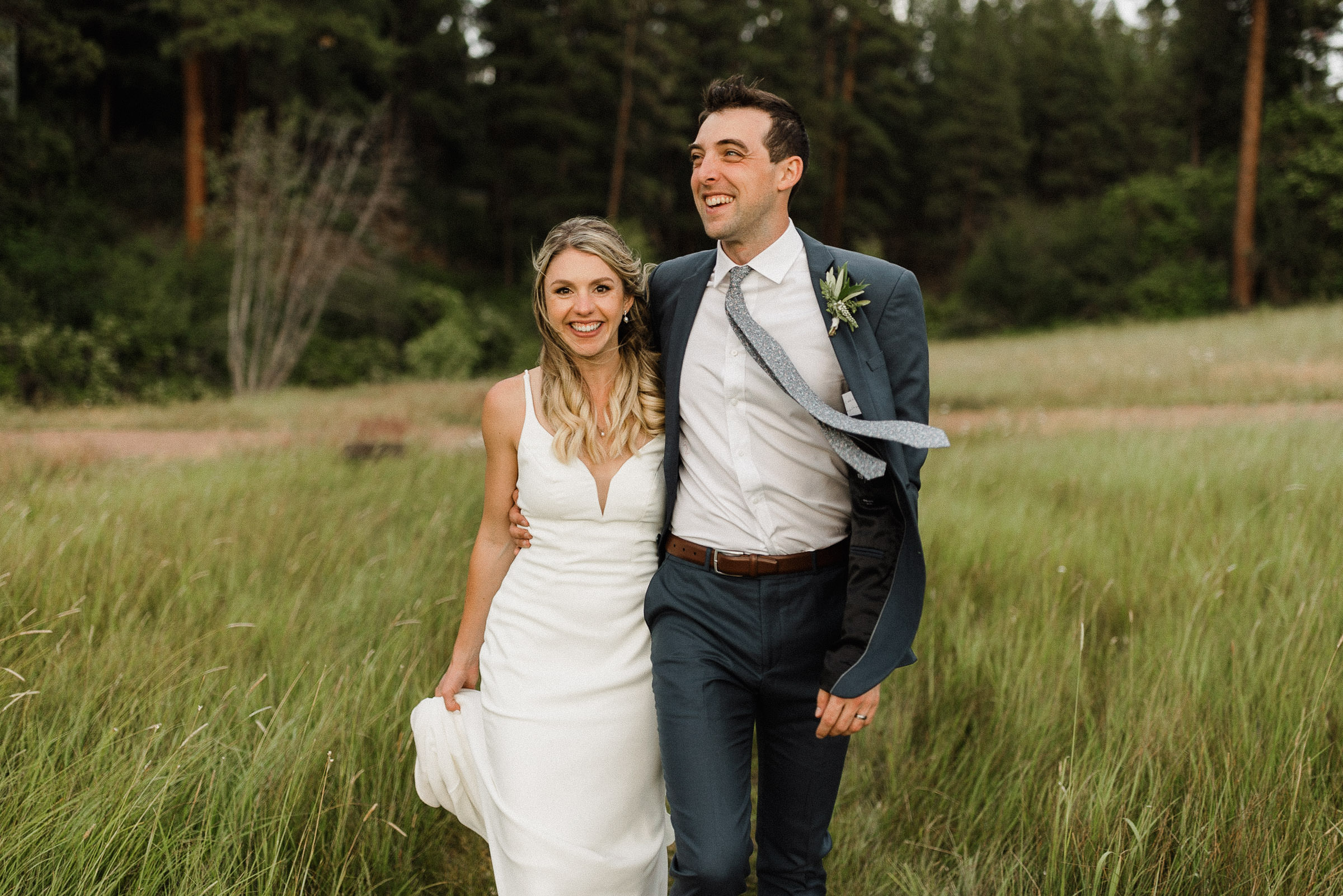 Bride and groom smile and walk together through a field